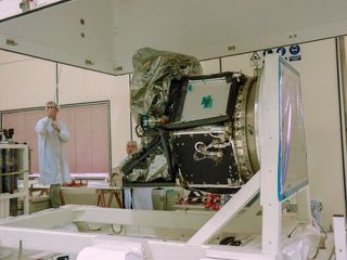 A test engineer lowers the upper part of a test container over CHEOPS in preparation for a propulsion-module leak test.