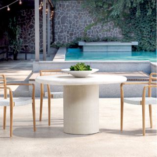 A circular modern outdoor dining table by a pool