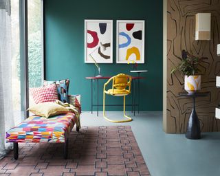 teal painted wall with desk and chaise longue, pink geometric rug, geometric artwork and wall
