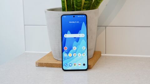 A Realme GT Neo 3 from the front, with the screen on, resting against a plant pot