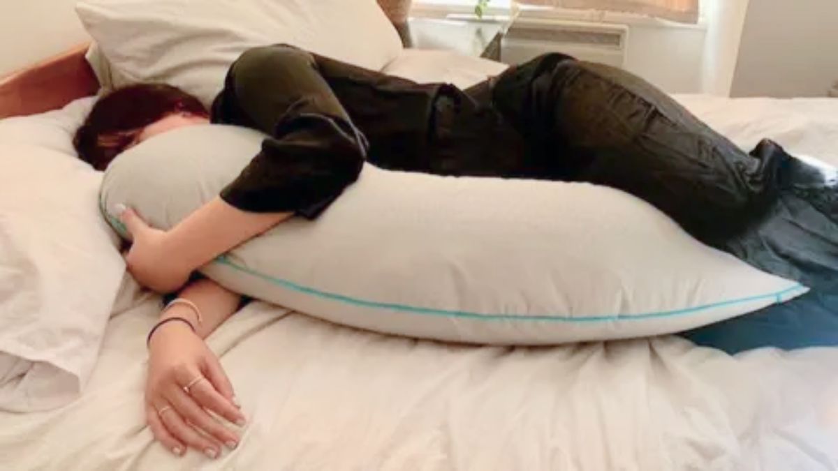 Woman sleeping on her side with a body pillow