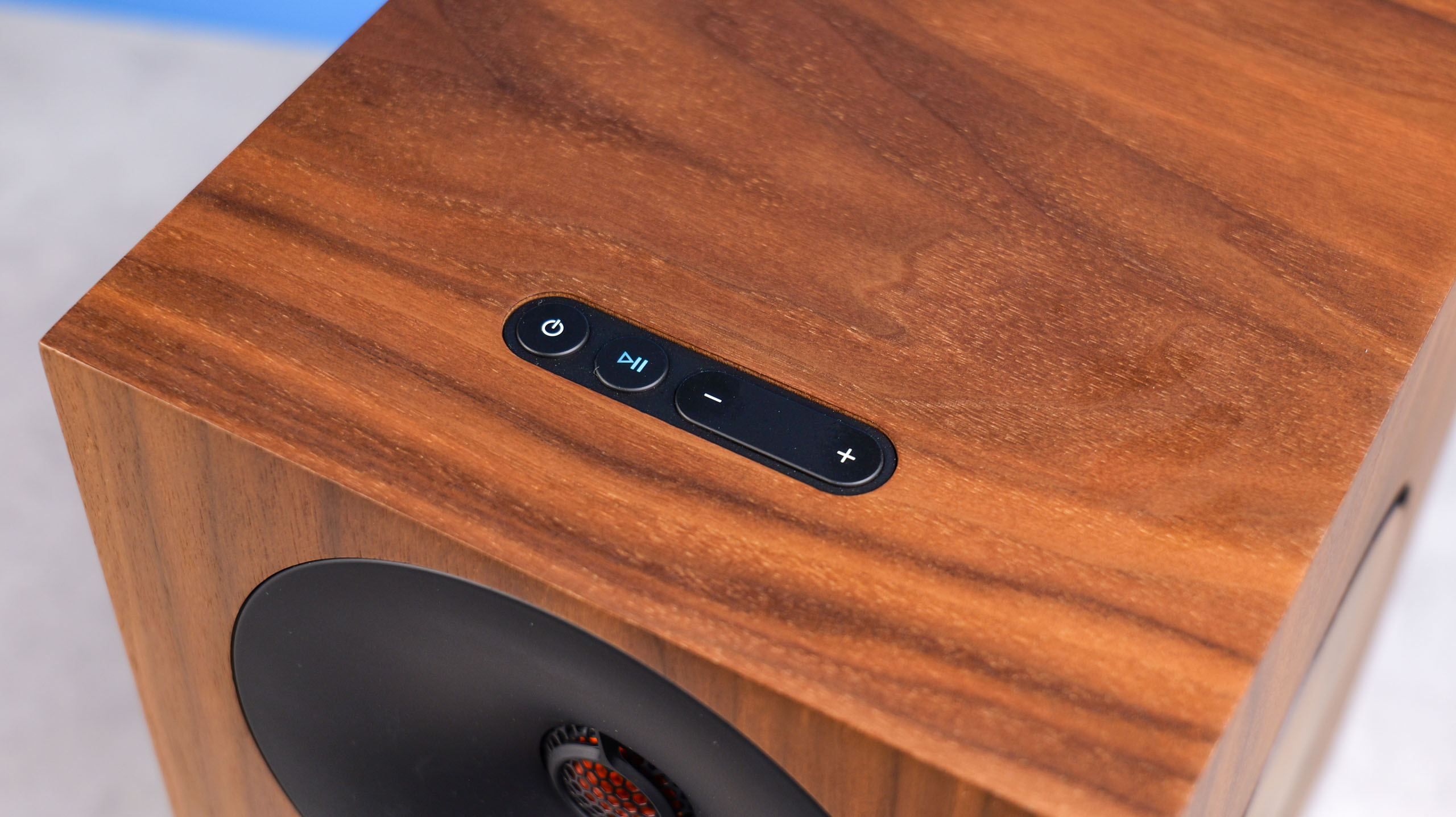 The Cambridge Audio L/R X top controls, positioned on a stone surface with a blue background