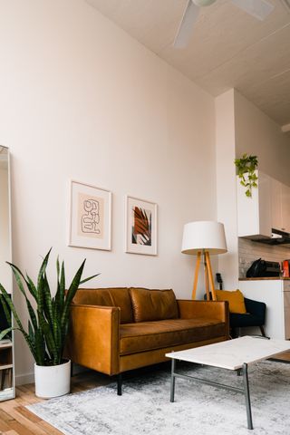 small living room in an apartment with a brown leather sofa and rug