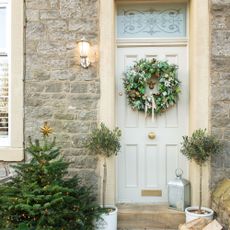 Green wreath on a beige front door with sandstone frame