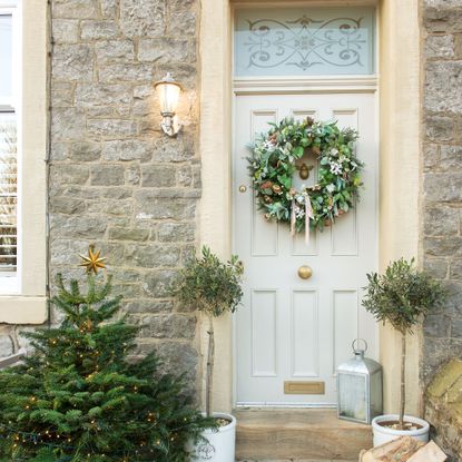 Green wreath on a beige front door with sandstone frame