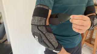 Man fixing the strap of 100% Fortis Elbow Guard