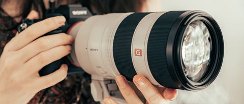Sony FE 70-200mm f/2.8 GM OSS II lens being held by the reviewer