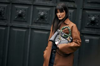 Leia Sfez is seen wearing a brown leather Hermes jacket, blue denim jeans, black belt and Hermes black bag with Kelly twilly charms outside Hermes show, during the Womenswear Fall/Winter 2024/2025 as part of Paris Fashion Week on March 02, 2024 in Paris, France.