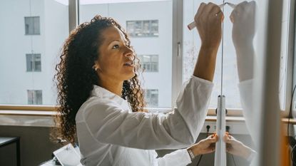 teacher writing on whiteboard with felt tip pen in classroom