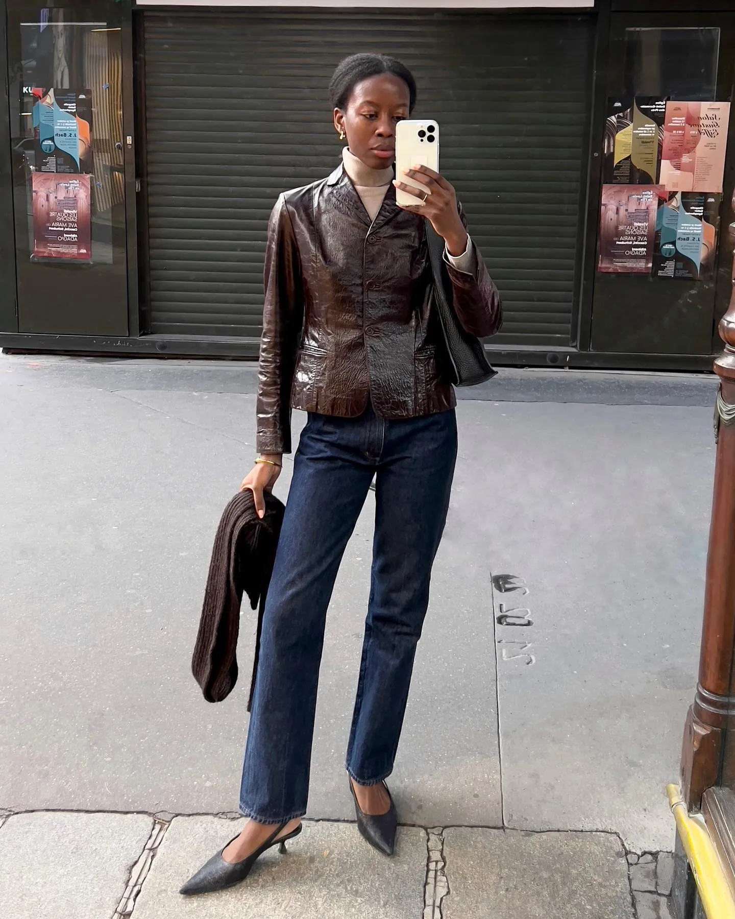 Sylvie wears brown leather jacket outfit with jeans on the streets of Paris.