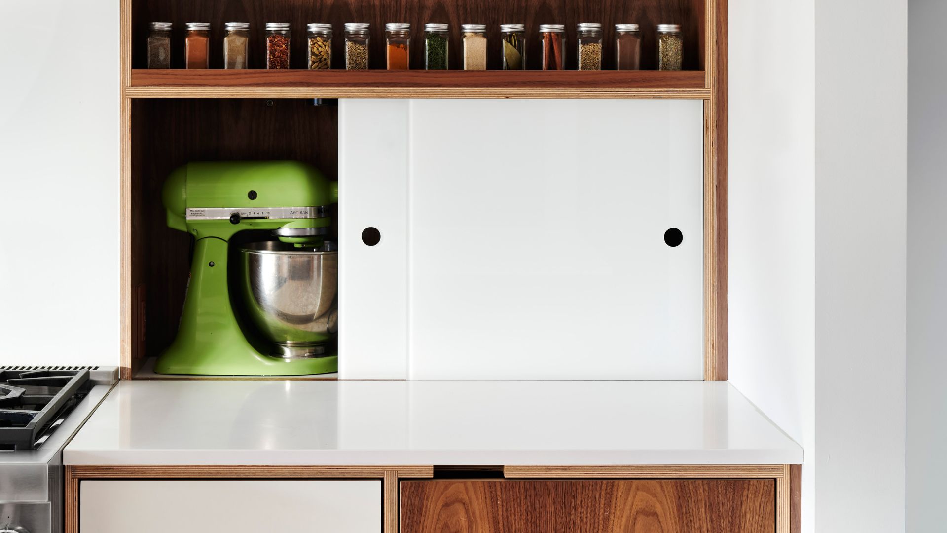 a white sliding door on a white countertop that is open to reveal a green mixer.