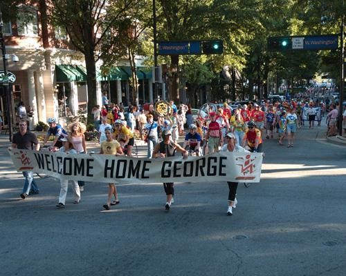 The crowd walks down main street
