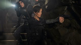 Charlize Theron's Andy holding gun and surrounded by armed allies in The Old Guard