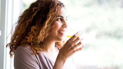 image shows a woman drinking a glass of water