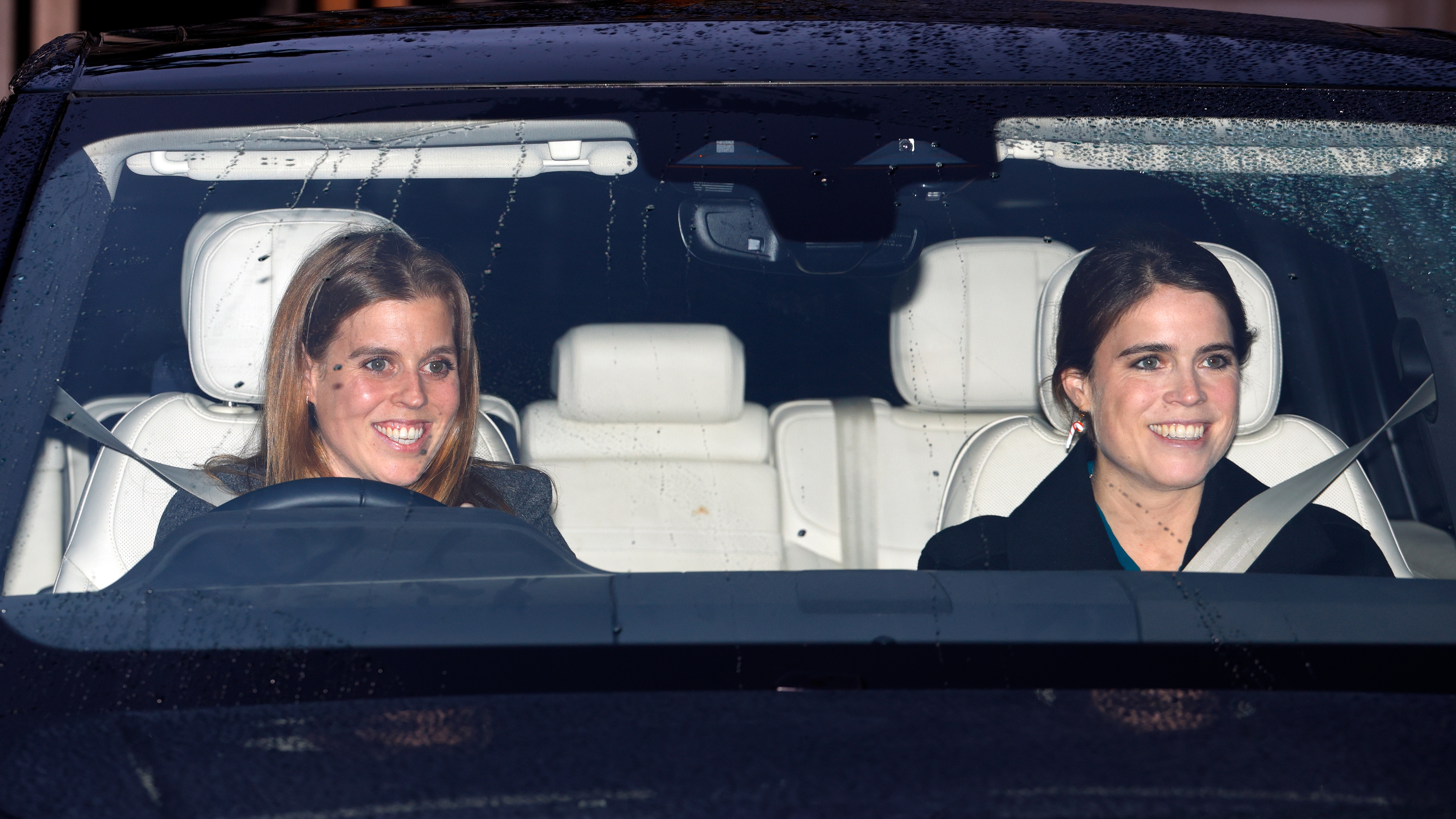 Princess Beatrice and Princess Eugenie smile as they drive to attend a Christmas Lunch for members of the Royal Family