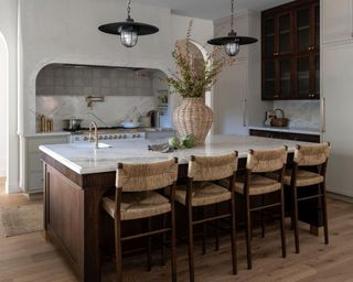 Kitchen with marble countertops, pendant lights, and rattan chairs