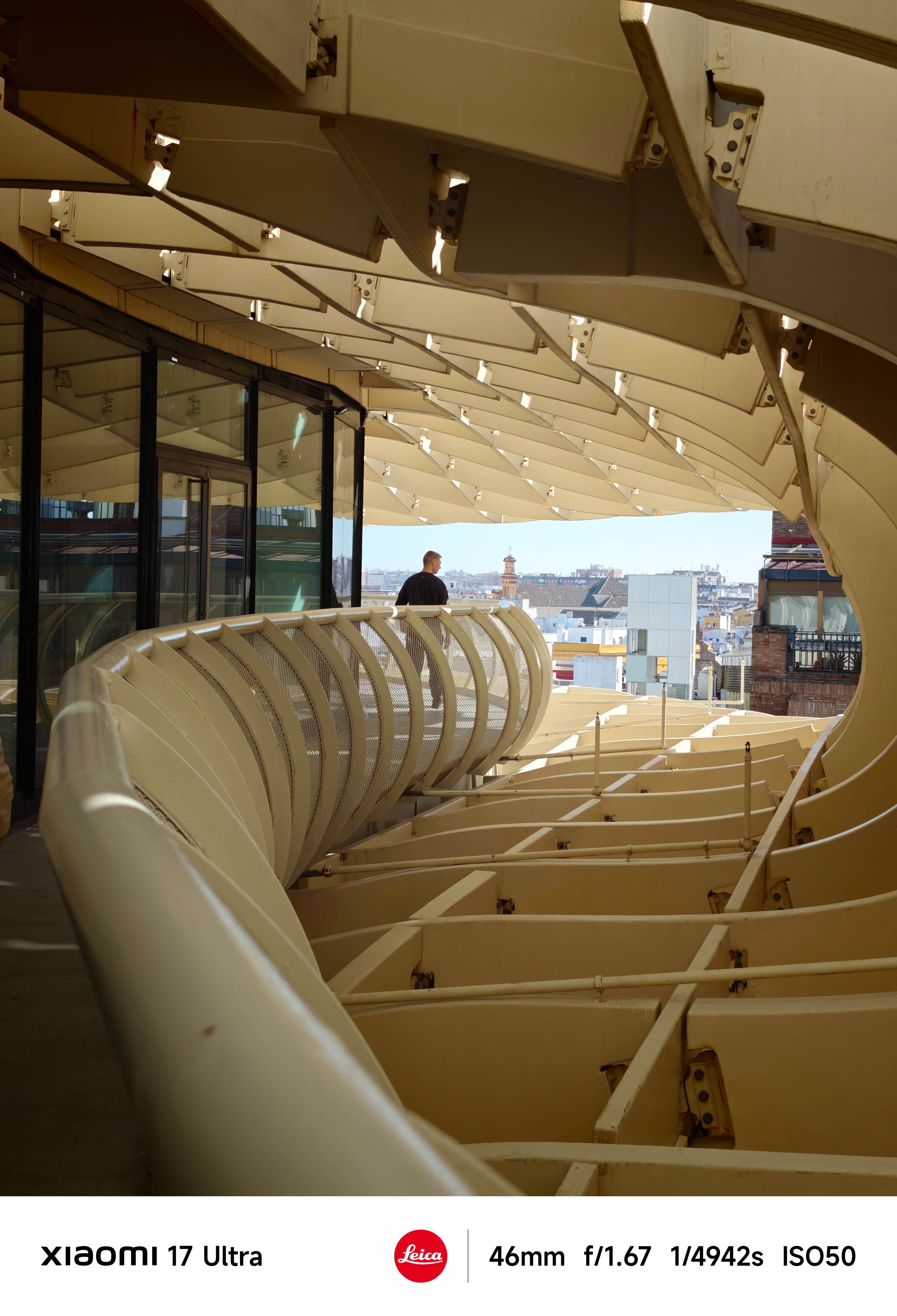 Curved walkway inside the Metropol Parasol with cream structural beams and city view beyond.