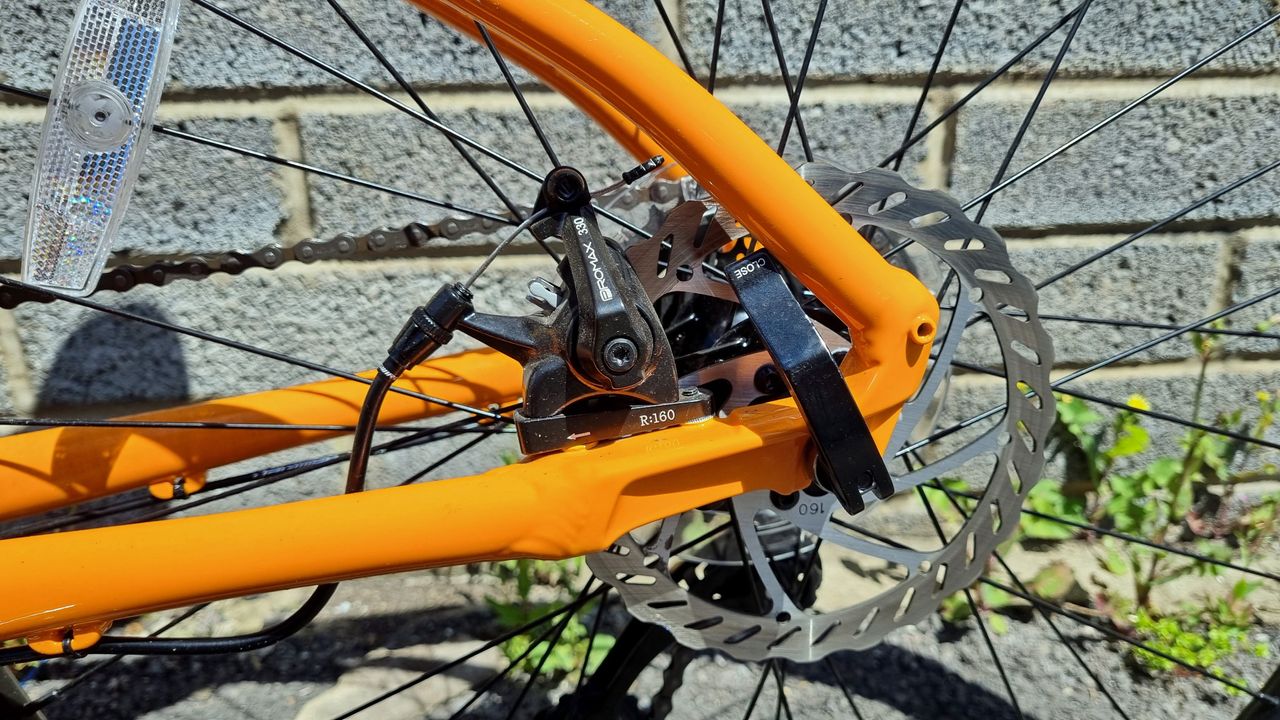A close up of a rear disc brake on an orange frame