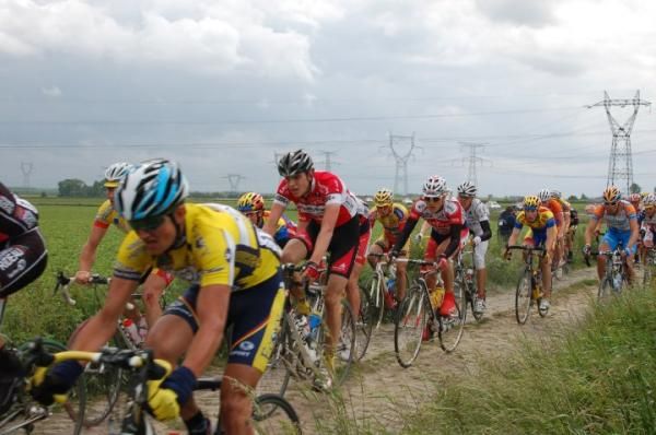 The peloton on a narrow, cobbled road