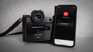 Leica SL3 camera on a wooden surface against a blue background