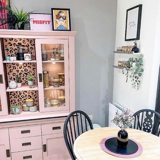 room with pink dresser and round table and chairs and shelves