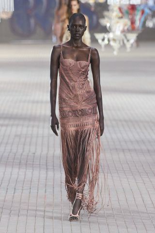 A woman at The Attico spring/summer 2025 show wearing pink heels with a pink fringe dress.