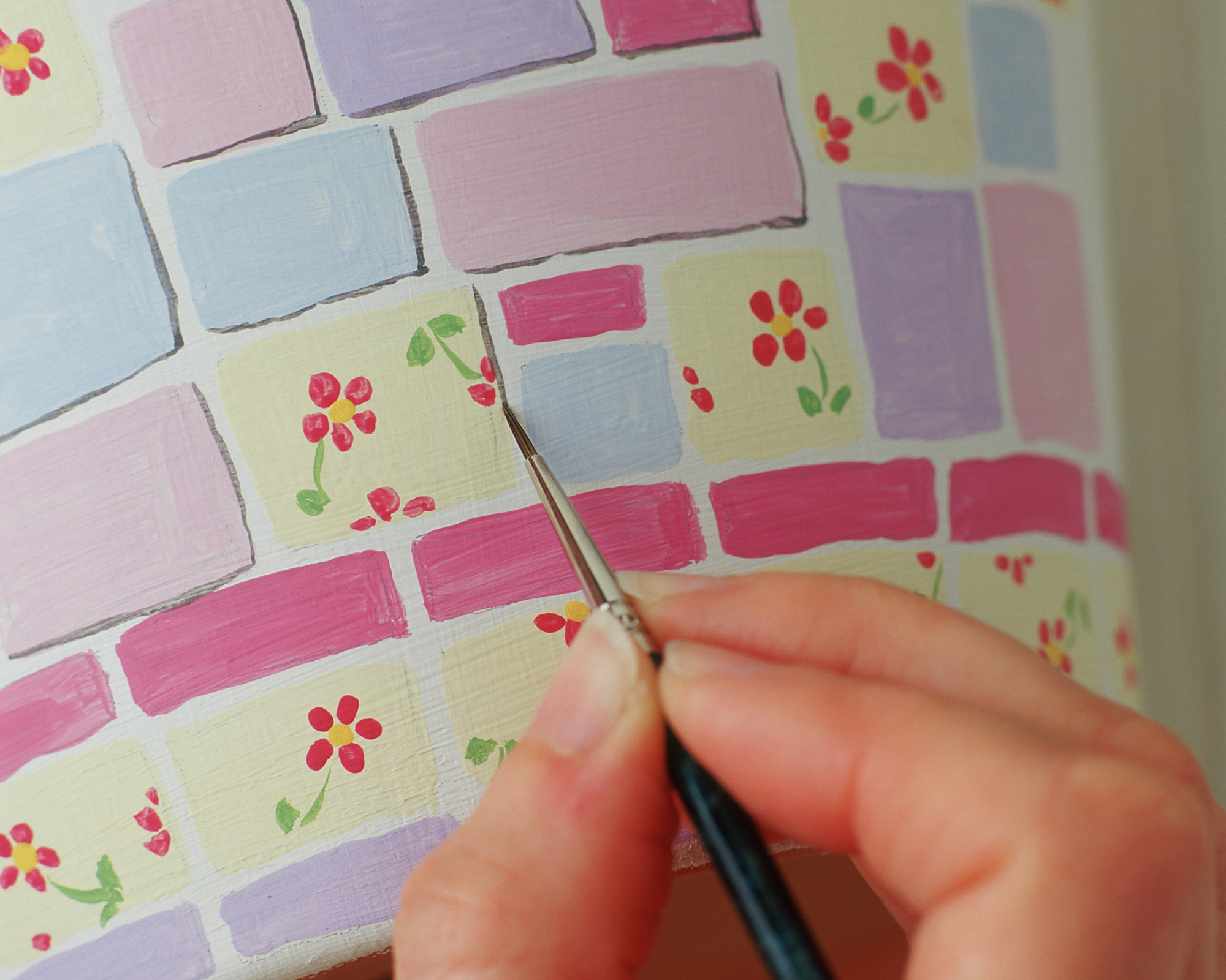 fine artist's paintbrush being used to add detail to a painted plant pot