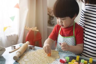 Young boy making cookies in the kitchen with flour on his nose