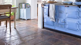 Kitchen with blue range cooker, tiled floor and wooden dining table and chair