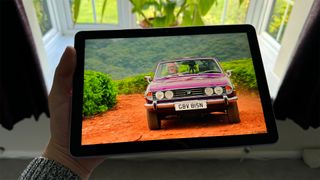 Amazon Fire HD 10 () tablet held in hand in front of window with car on screen