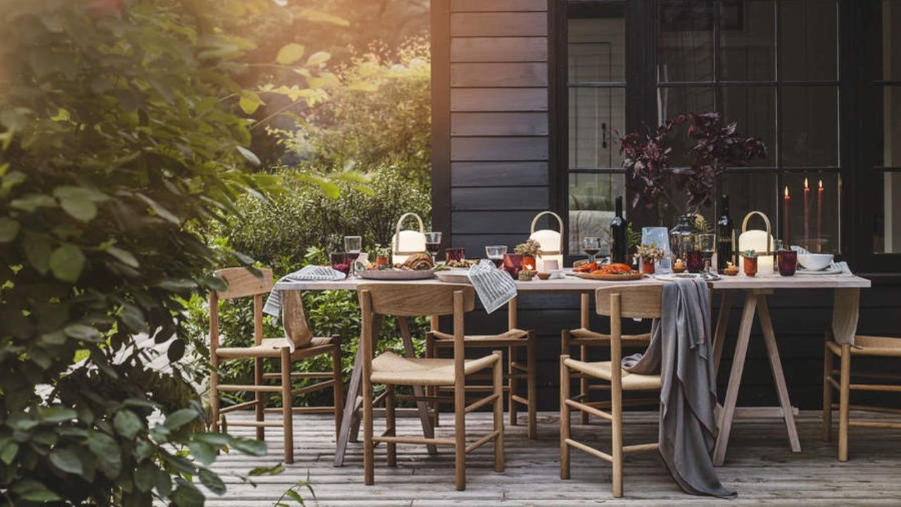 An outdoor dining table set up for dinner at sunset with candles 