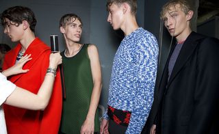 A queue of models in a dark room, one looking at the camera