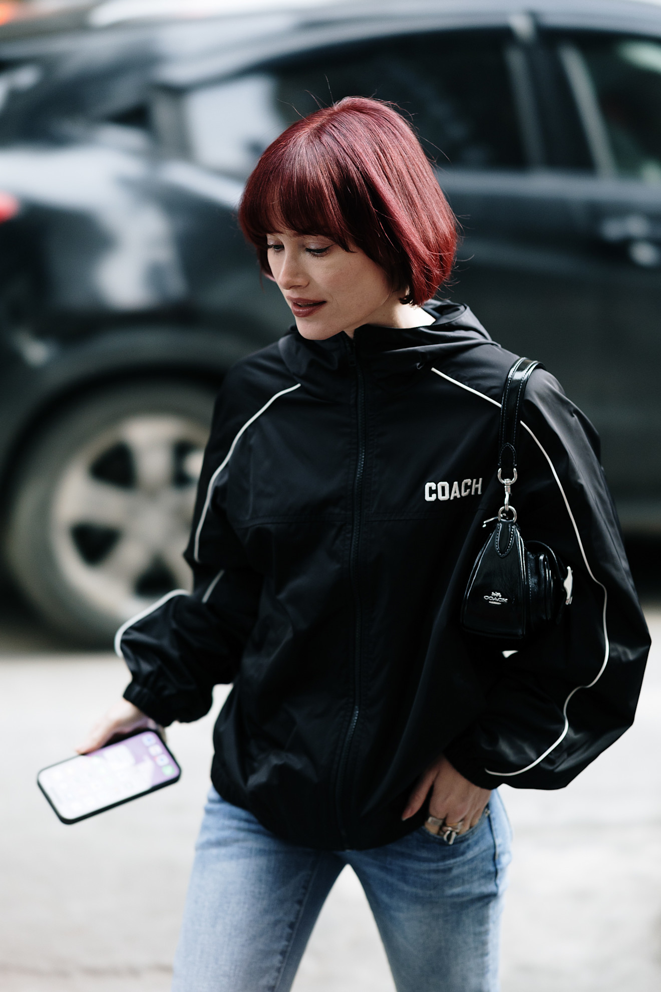 a woman with a short bob haircut in a maroon color with a black jacket and jeans