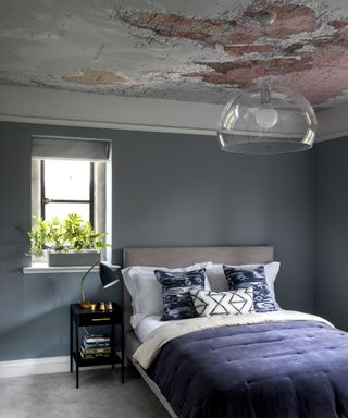 A teenage boys bedroom idea with blue wall, blue bed and atlas wallpaper on the ceiling