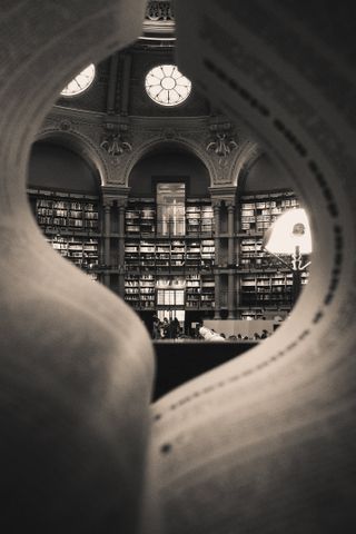 Elegant library interior viewed through open book pages, highlighting ornate architecture and books