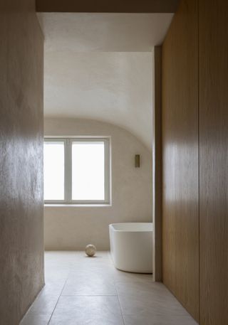 A minimalist bathroom with a white bath and a window