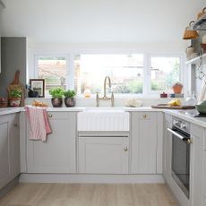 Grey kitchen with white painted walls and white wountertops with a white sink in the middle