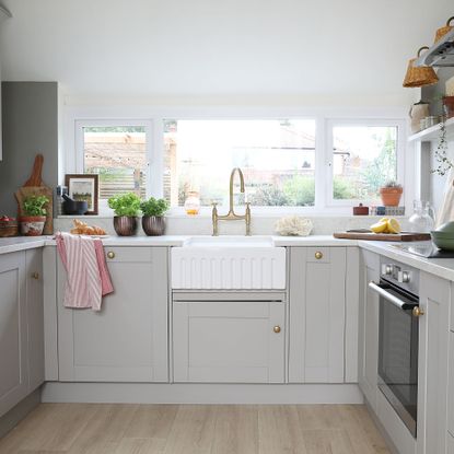 Grey kitchen with white painted walls and white wountertops with a white sink in the middle