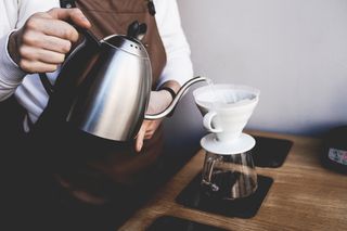 Water being poured into a pour over coffee dripper, positioned on a set of scales
