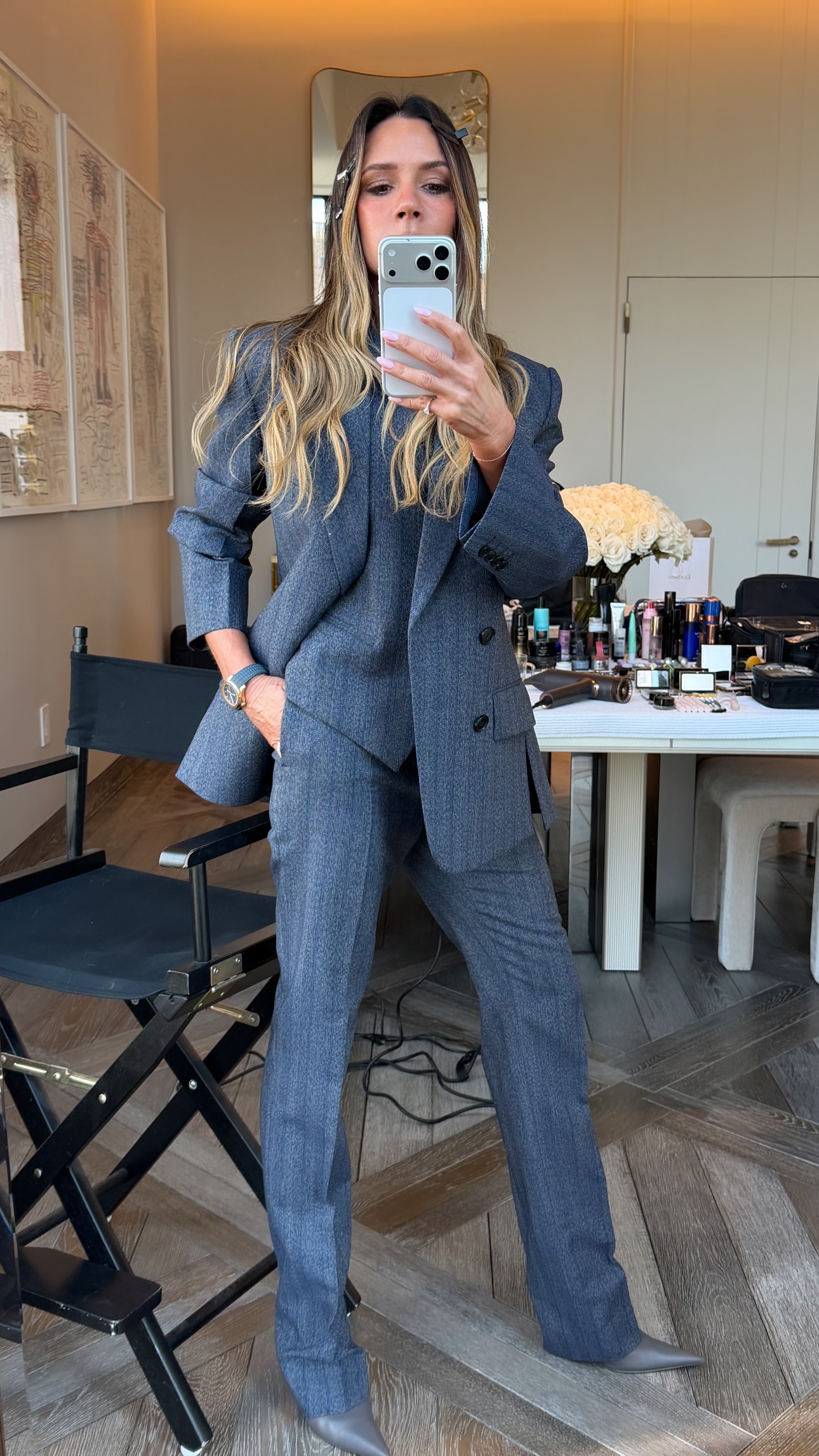 Victoria Beckham takes a mirror selfie wearing s dark grey three-piece suit with grey pointed-toe heels.