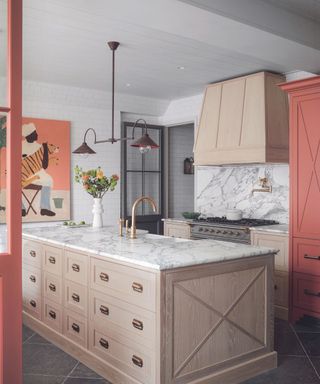 A kitchen with beige cabinetry, white countertops, and peachy accents on the walls