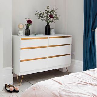 white bedroom with drawer and flower vase