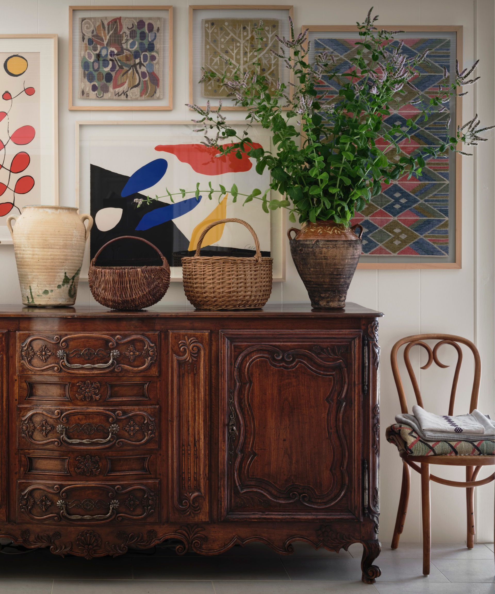 An antique stable surrounded by baskets, a chair and artwork.
