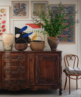 A vintage hutch surrounded by baskets, a chair and artwork