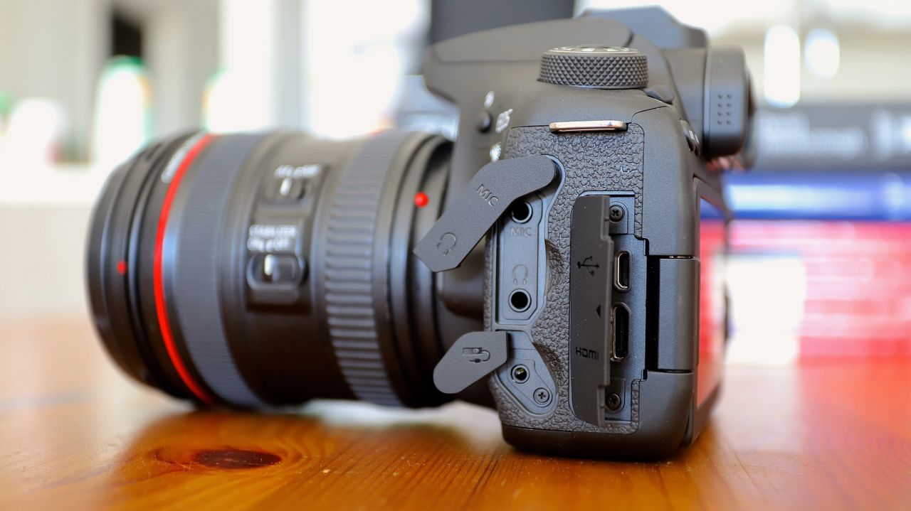 Canon EOS 90D DSLR on a table, connection port doors open