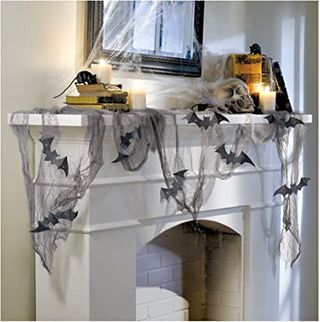Best Halloween decorations: an image of the Halloween Party Draping Gauze Decoration & Glitter Bats Kit decorating a spooky fireplace