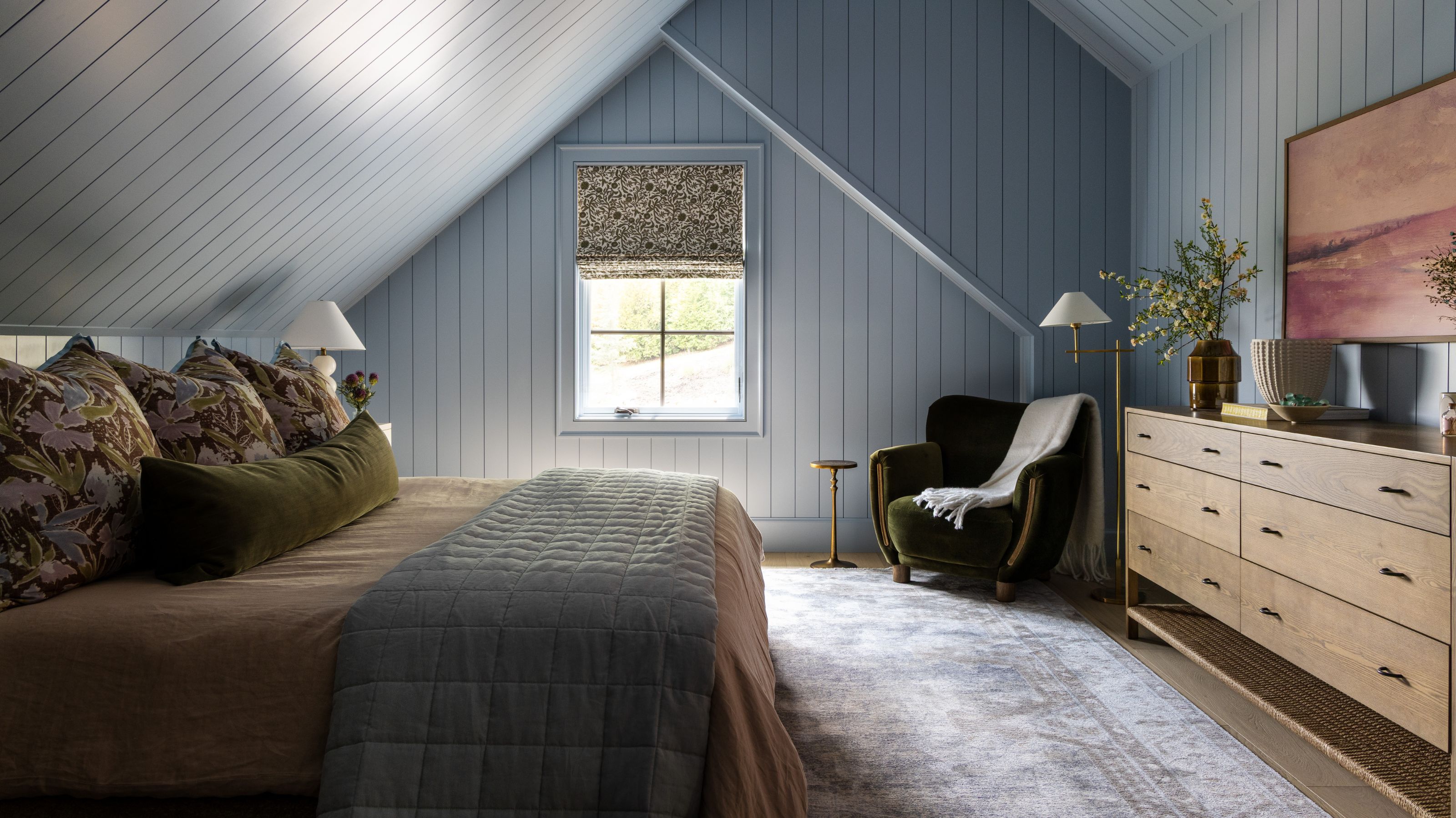 a blue valted paneled bedroom with a large oak console and vintage rug