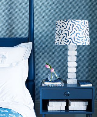 Blue and white bedroom with patterned wallpaper and blue side table