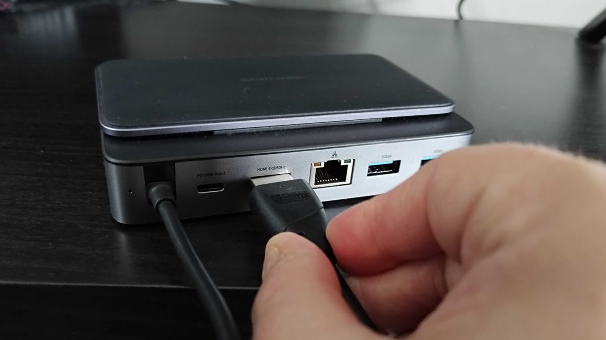 Hand inserting HDMI cable into Baseus 6-in-1 Steam Deck dock