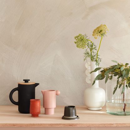 Mugs and teapot and decorative vase displayed on wooden surface